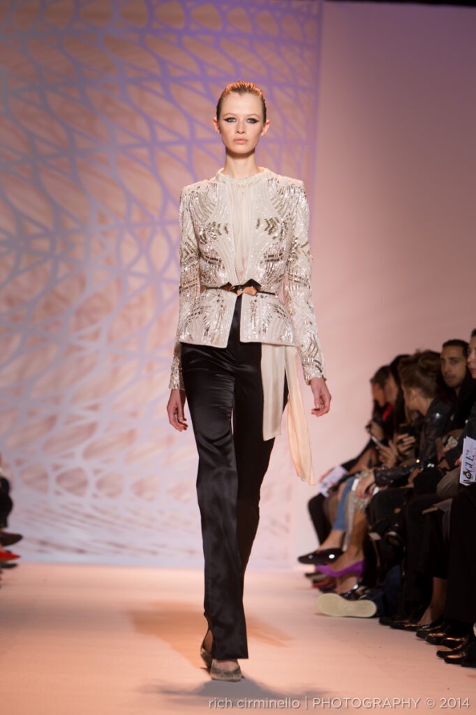 This image showcases a model wearing a luxurious black Zuhair Murad gown featuring stunning white detailing at Paris Haute Couture Fashion Week 2014, held at the Palais des Beaux-Arts. The bold contrast of the gown’s intricate patterns and embellishments highlights Murad’s extraordinary attention to detail. Photographed by Dallas-based fashion photographer Rich Cirminello, this image beautifully illustrates the gown’s balance of elegance and modernity.