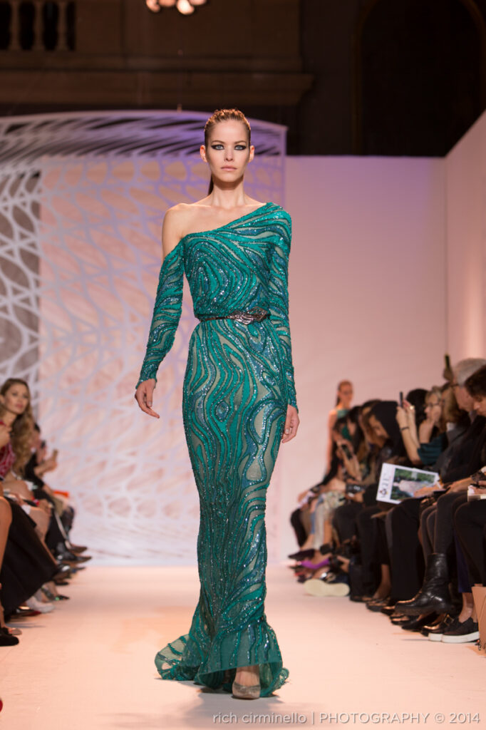 Model in a long teal Zuhair Murad gown with sequins walking the runway at Paris Haute Couture Fashion Week 2014. Photography by Rich Cirminello.