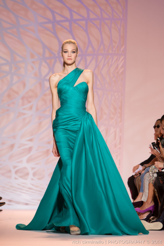 Model in a teal Zuhair Murad gown with a draped train walking the runway at Paris Haute Couture Fashion Week 2014. Photography by Rich Cirminello.