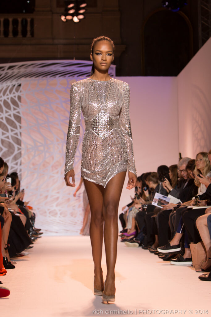 Model walking in a sparkling silver long-sleeved mini dress at Zuhair Murad’s 2014 Paris Haute Couture Fashion Week, photographed by Rich Cirminello.