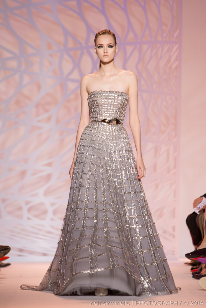 Model wearing a silver strapless gown with a grid-like pattern on the runway at Zuhair Murad’s 2014 Paris Haute Couture Fashion Week, photographed by Rich Cirminello