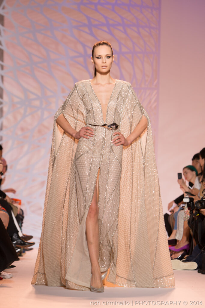 Model in an embellished gown with a cape on the runway during Zuhair Murad's 2014 Paris Haute Couture Fashion Week show, photographed by Rich Cirminello.