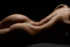 Back and hips of a reclining figure in warm side light, bodyscape photography